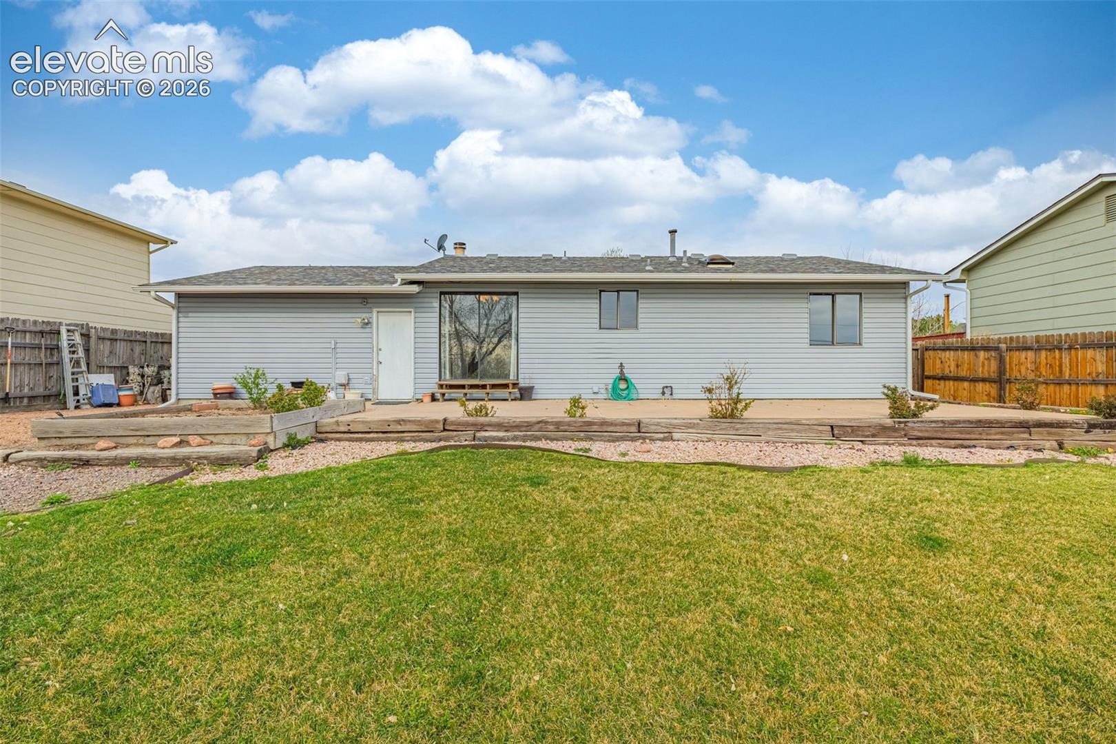 Back of house features fenced yard, concrete patio, flat grassy space and plenty of space for your gardening dreams!
