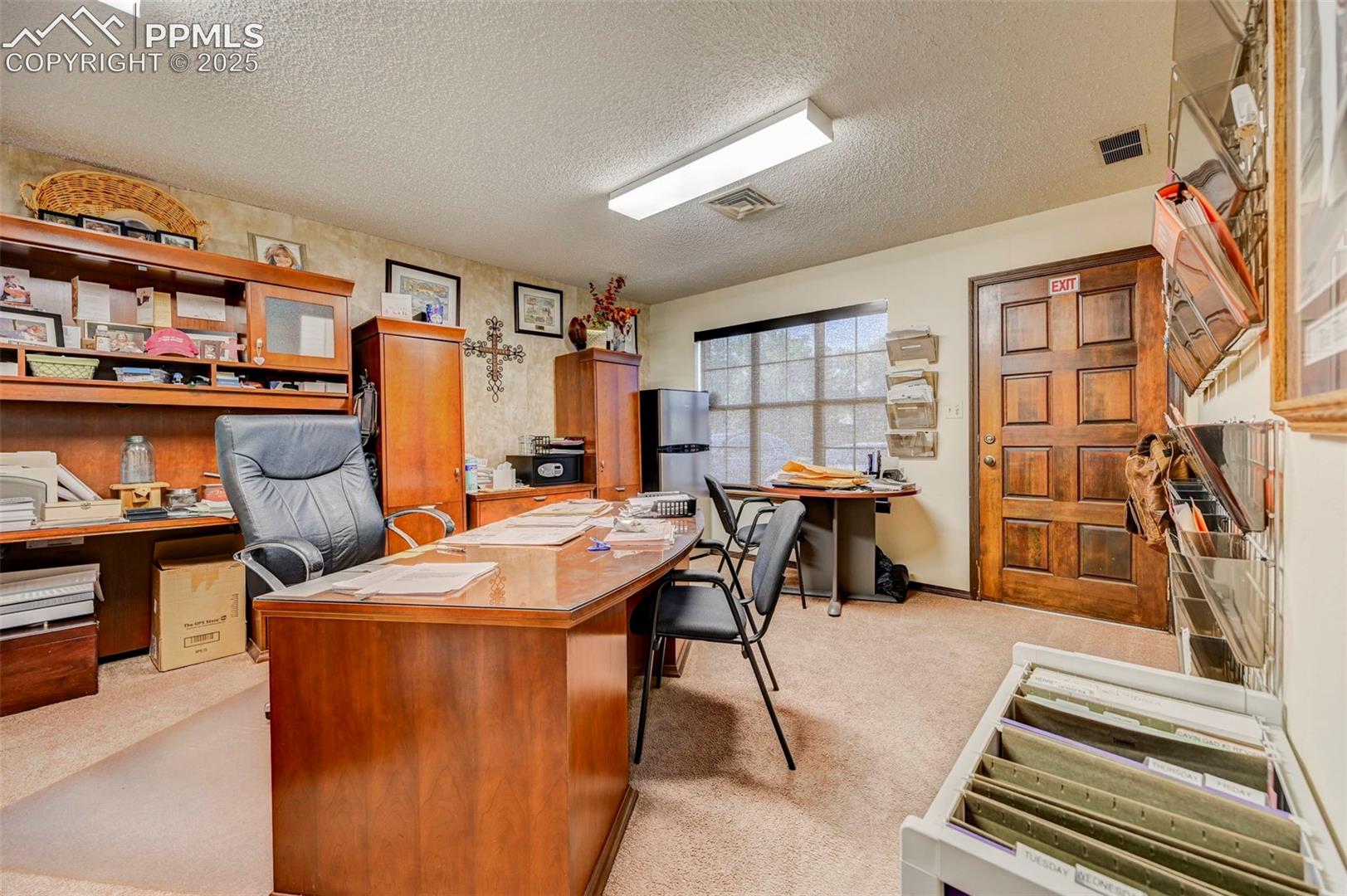 Home office with light carpet and a textured ceiling
