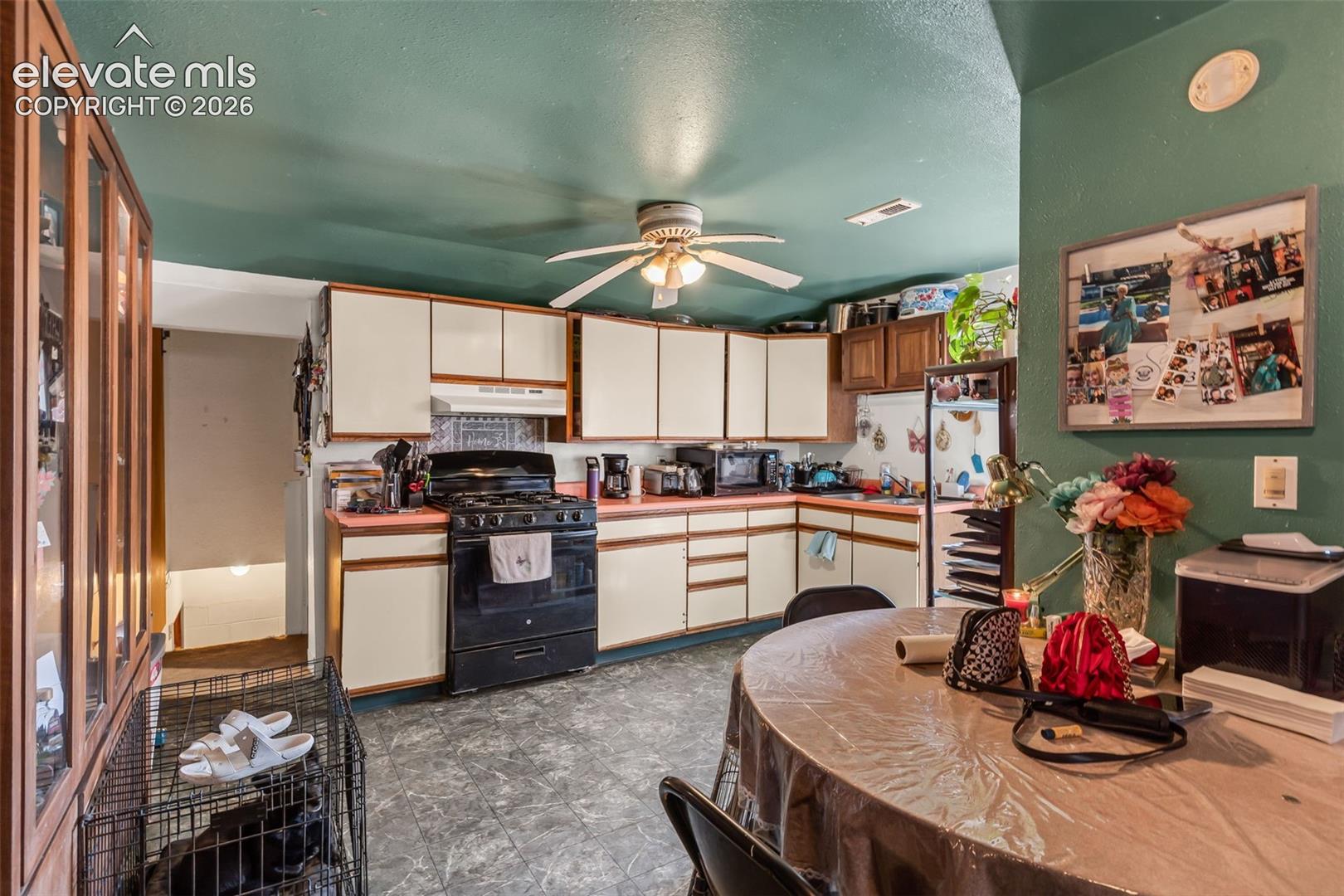 L-shaped kitchen with white cabinetry and a built-in oven, featuring a ceiling fan with light fixture