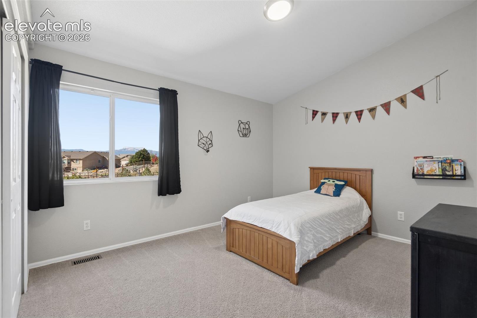 Carpeted room with a vaulted ceiling, recessed lighting, and a window offering a distant mountain landscape