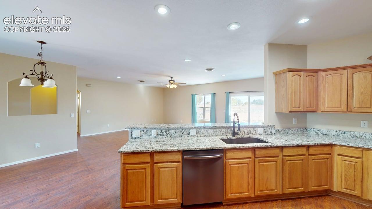 Kitchen with granite countertops, wood-finish cabinetry, stainless steel dishwasher, and a double basin sink with a gooseneck faucet