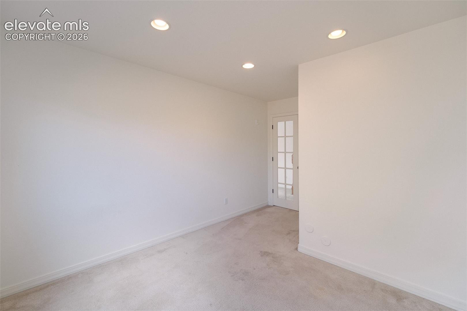 Recessed lighting, light-toned carpeting, and a french door with multi-pane glass