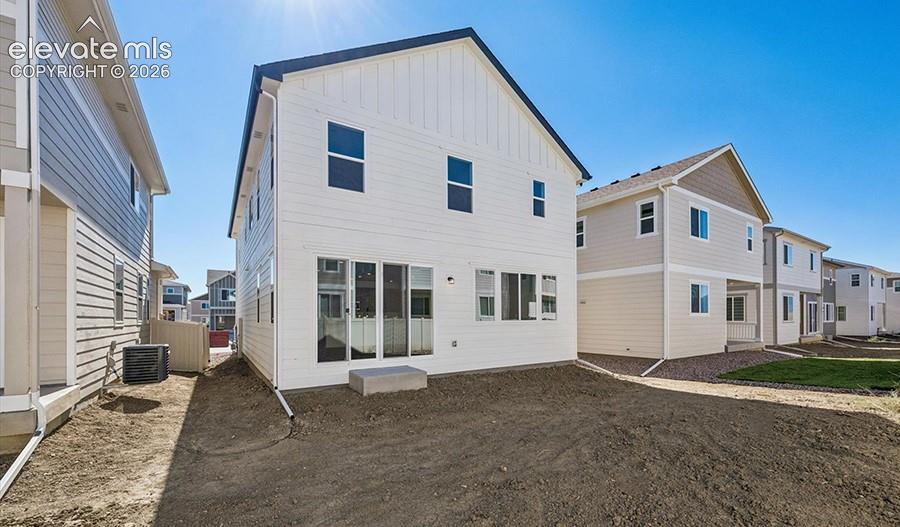 Two-story exterior featuring white board-and-batten siding, a gable roofline, and sliding glass doors with a concrete stoop