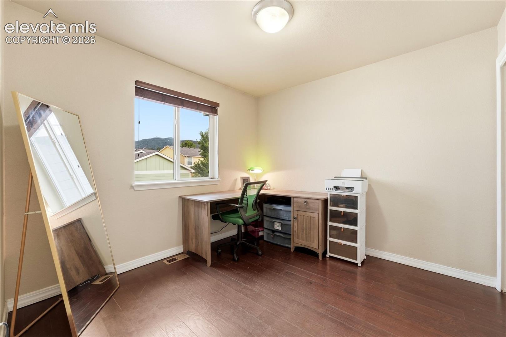 Hardwood flooring, painted walls, white trim, window with blinds, and a flush mount ceiling light