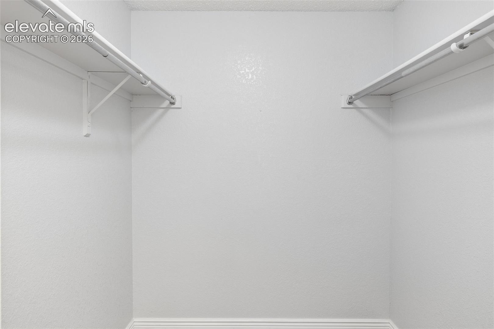Storage space featuring dual upper shelving units with integrated garment rods