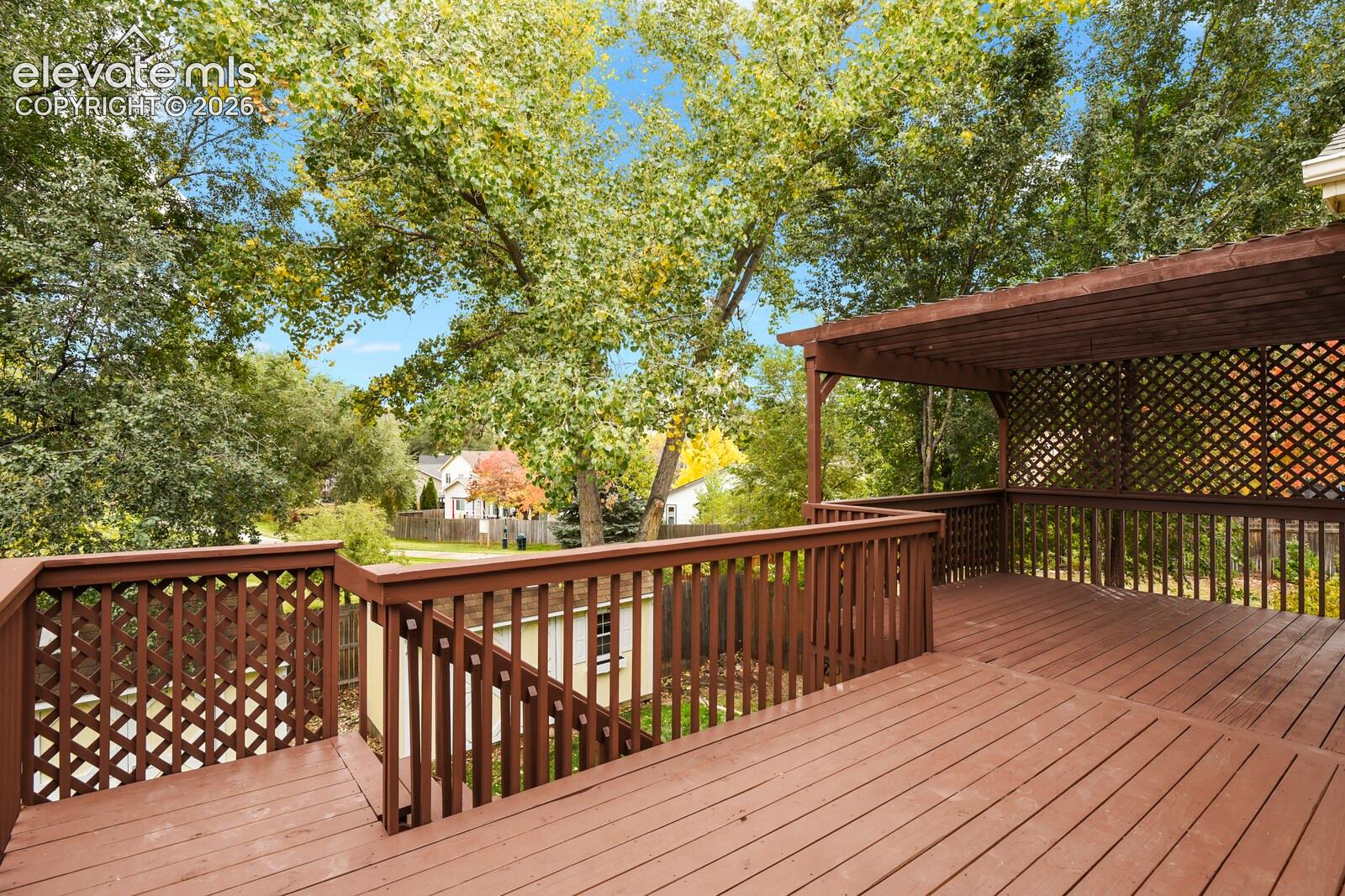 Extra large wood deck featuring a built-in pergola, lattice privacy screening, and stairs leading to the yard