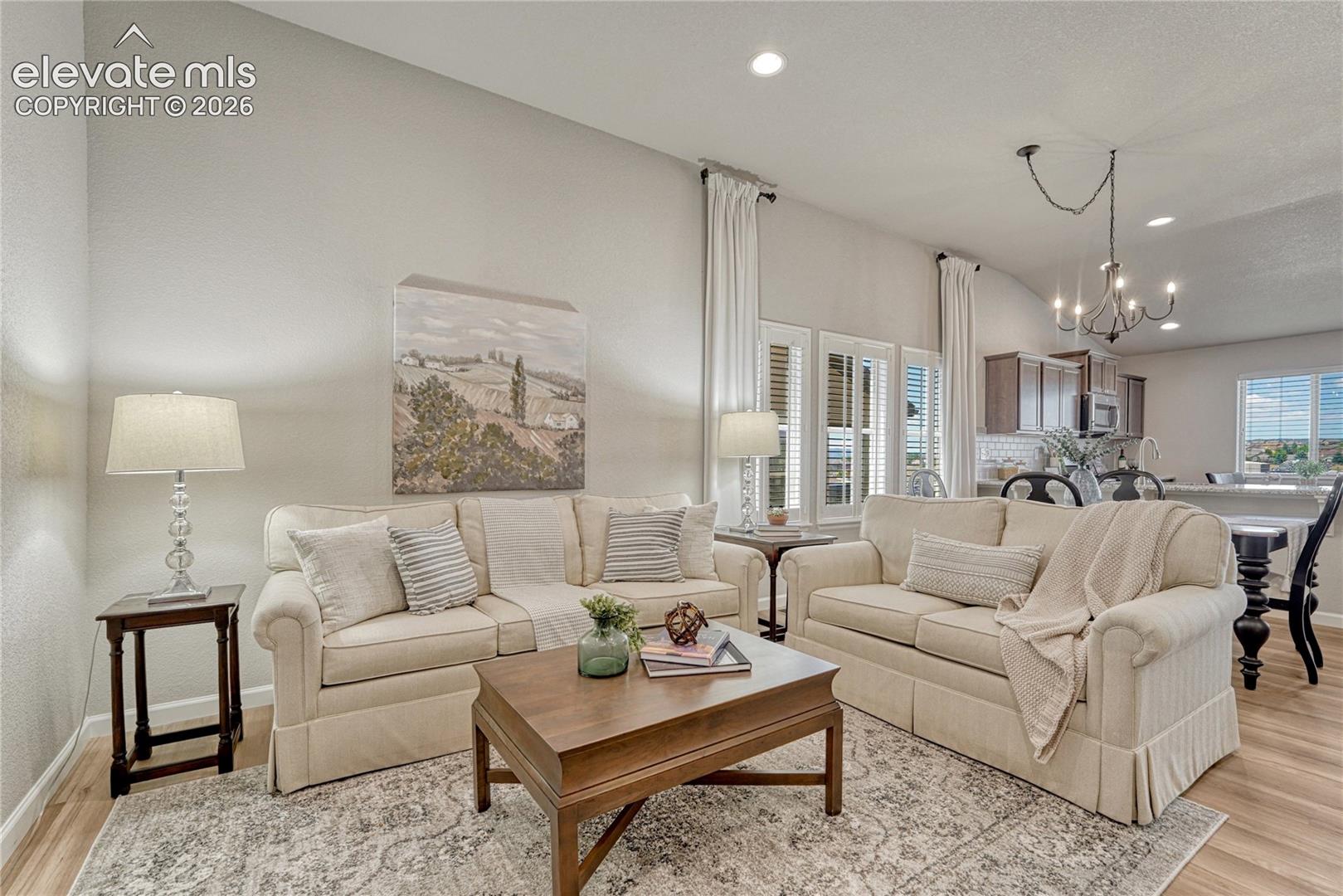 Vaulted ceilings and abundant natural light enhance the open-concept living area, creating an environment that flows naturally between the kitchen, dining area, and living room.
