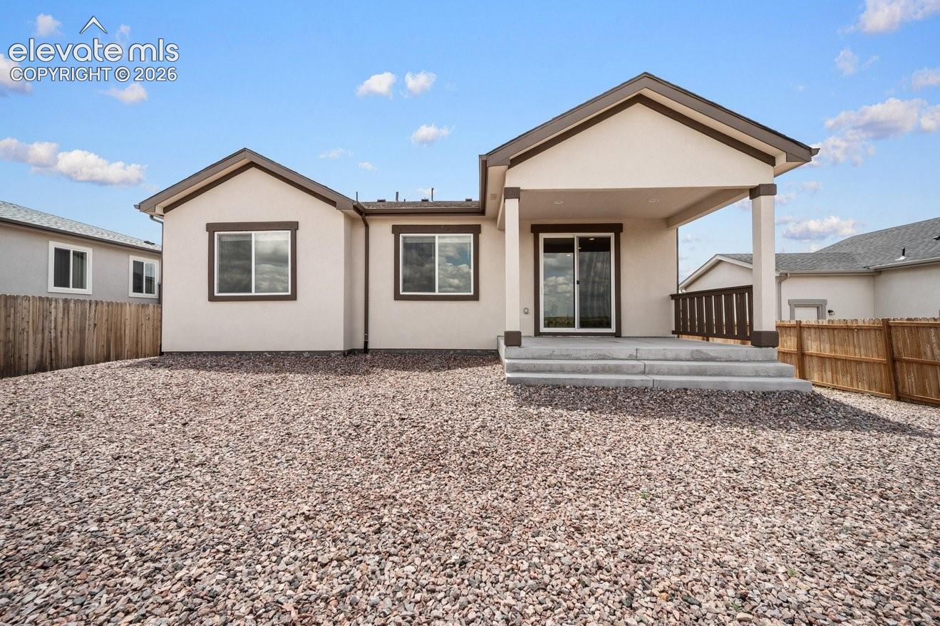Rear exterior featuring a covered patio, concrete steps, sliding glass door, and multiple windows with dark trim