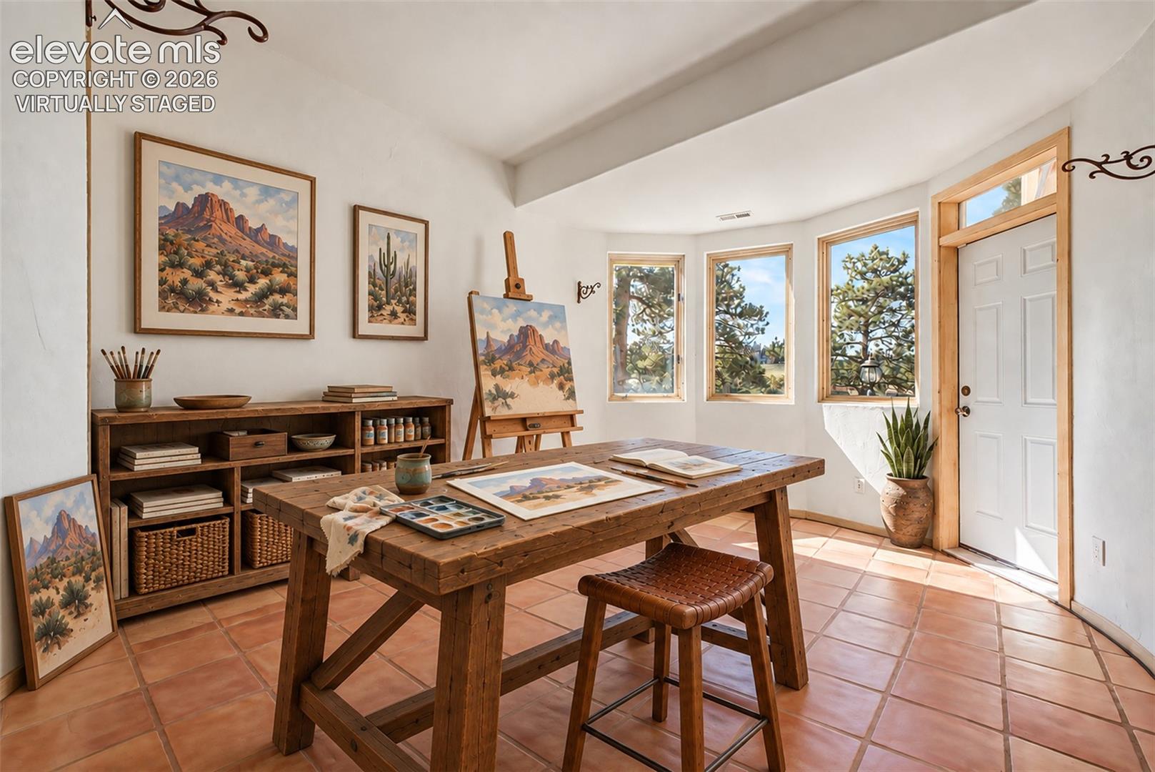 Virtually Staged
Warm terracotta tile flooring, a built-in wooden shelving unit, a white paneled door with wooden trim, and multiple windows offering external scenery