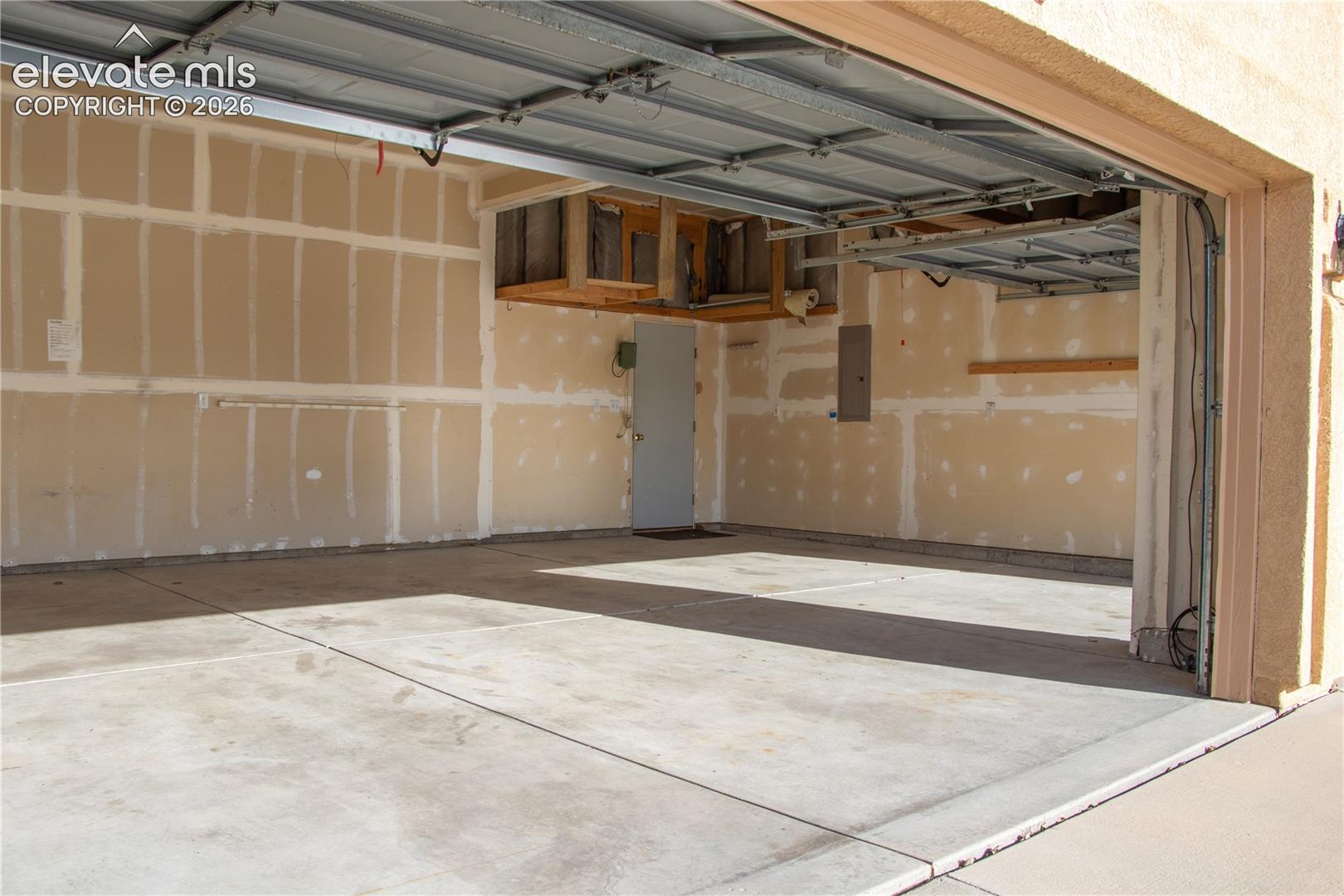 Spacious garage featuring a concrete floor, an overhead garage door mechanism, and a side access door