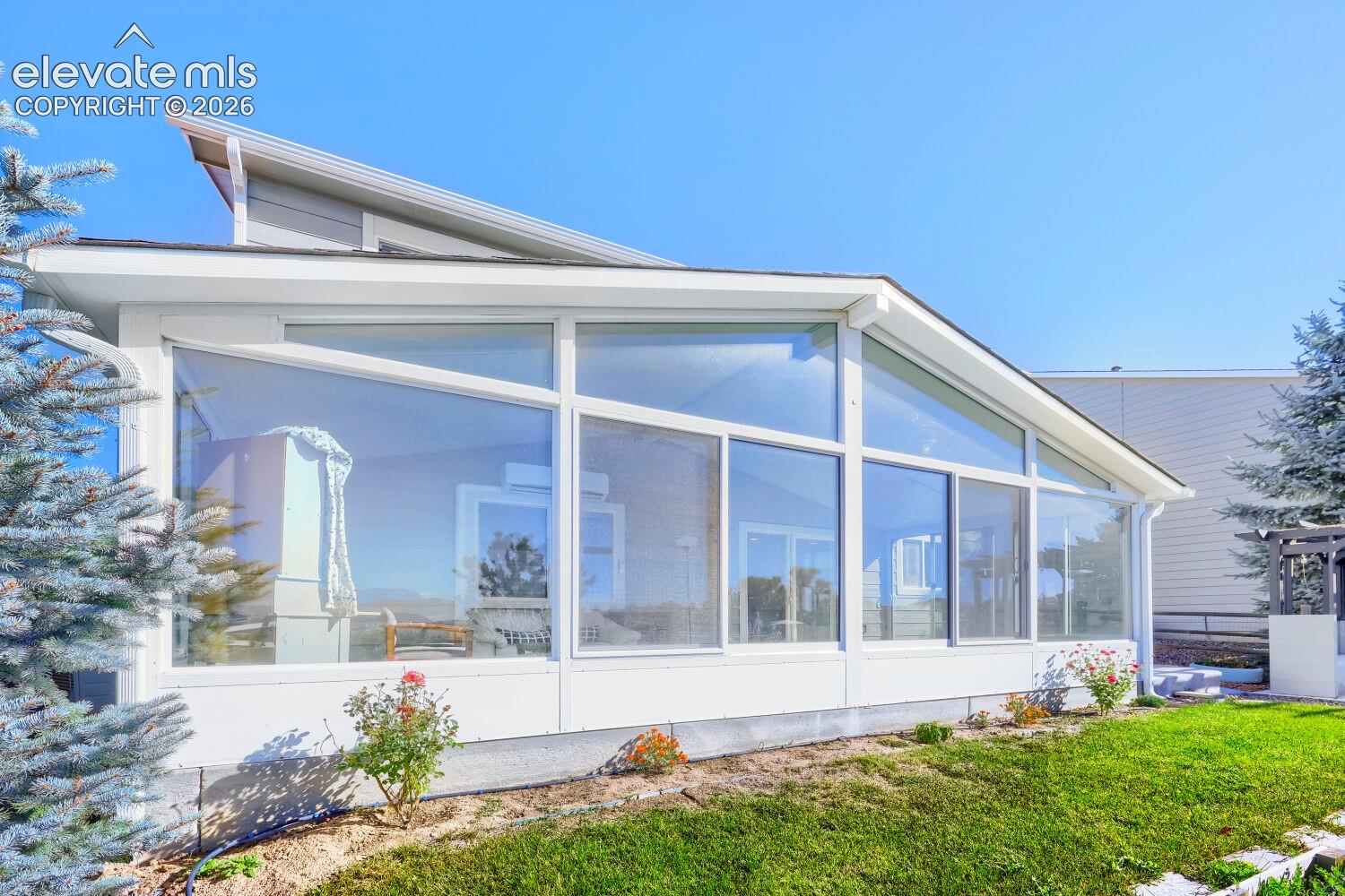 Sunroom addition featuring vaulted ceilings, floor-to-ceiling glass paneling, white-painted framework, and integrated sliding doors