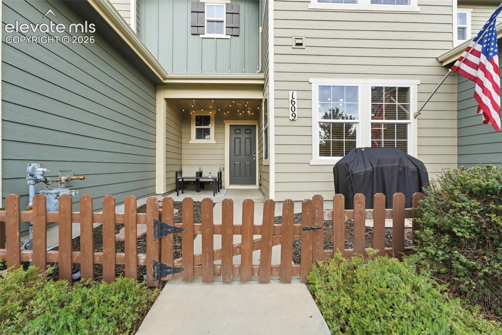 Covered entry with recessed lighting, wood-finish picket fence, and horizontal siding