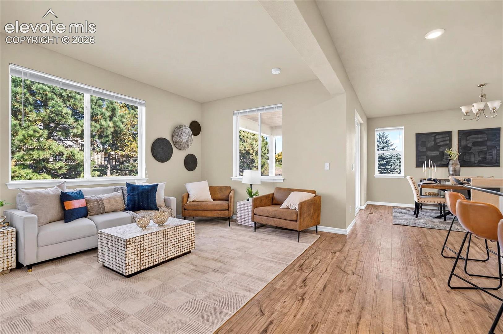 Open-concept living space with abundant natural light, recessed lighting, and wood-laminate finish flooring