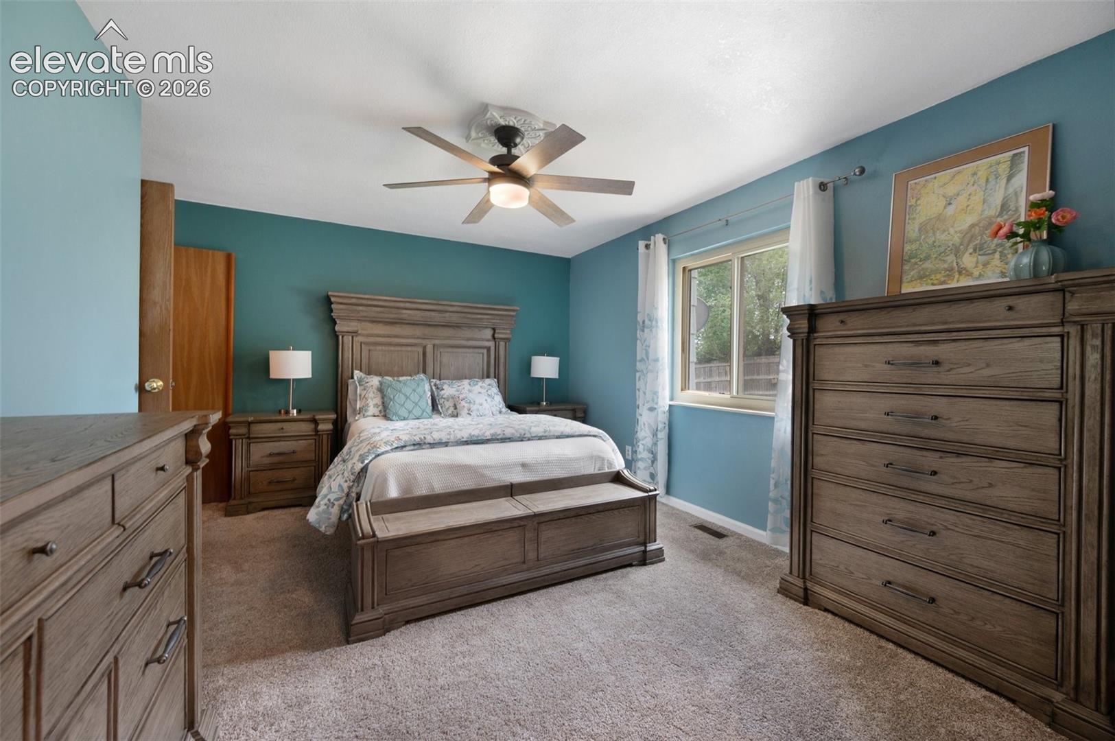 Bedroom featuring light carpet, ceiling fan, and baseboards