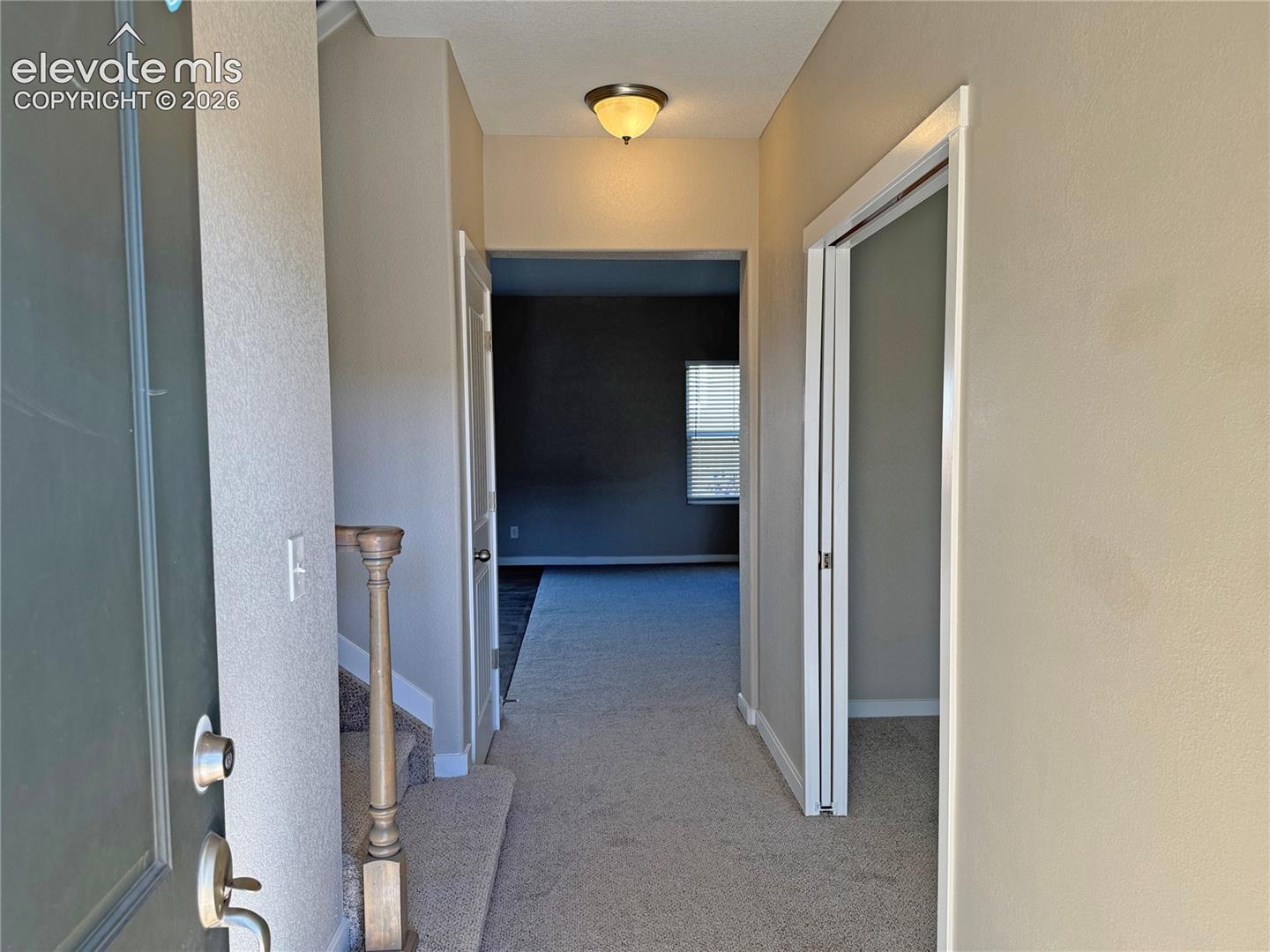 Entryway featuring neutral wall tones, carpeted flooring, a dome-style ceiling light fixture, and a wooden staircase banister