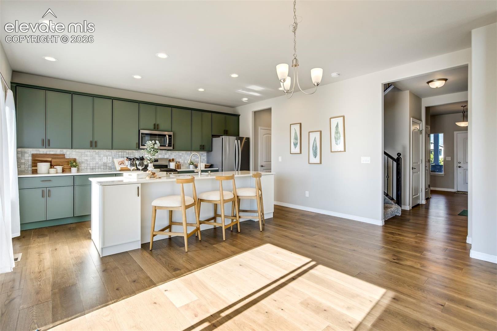 Expansive kitchen island with white countertop, recessed lighting, wood-finish flooring, and green cabinetry