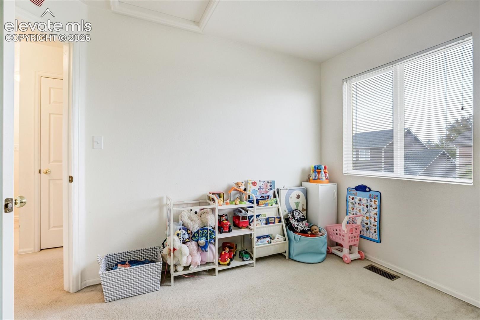 Carpeted room featuring a large window with blinds and white interior doors