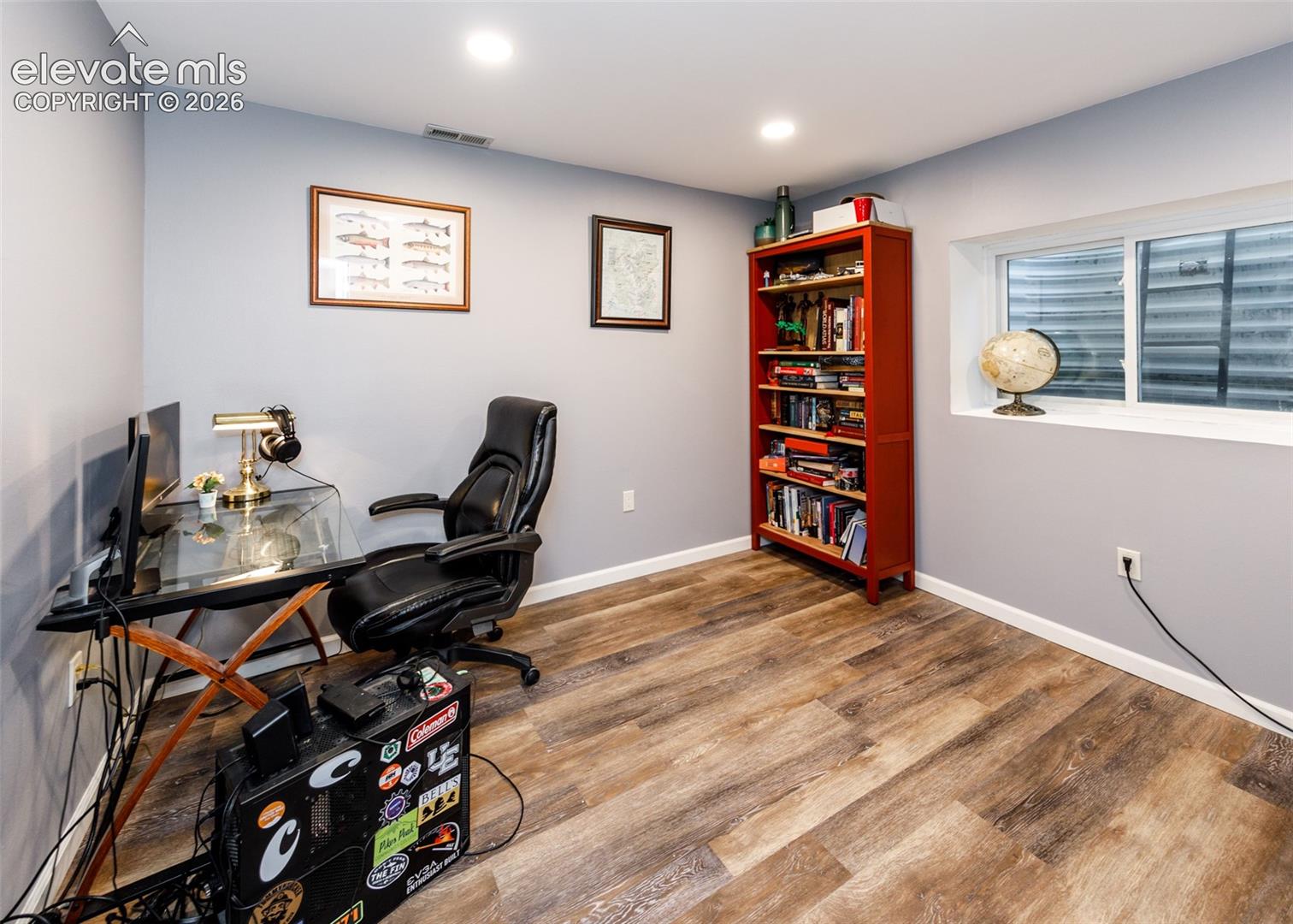 Wood-finish flooring, recessed lighting, built-in shelving, a large window, and light gray wall paint
