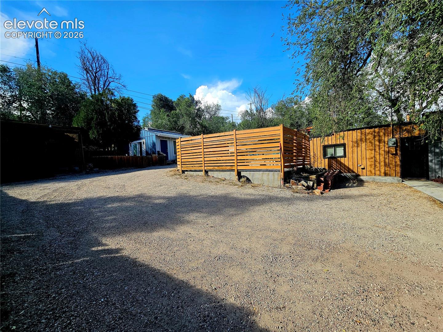 Gravel lot with a horizontal slat privacy fence