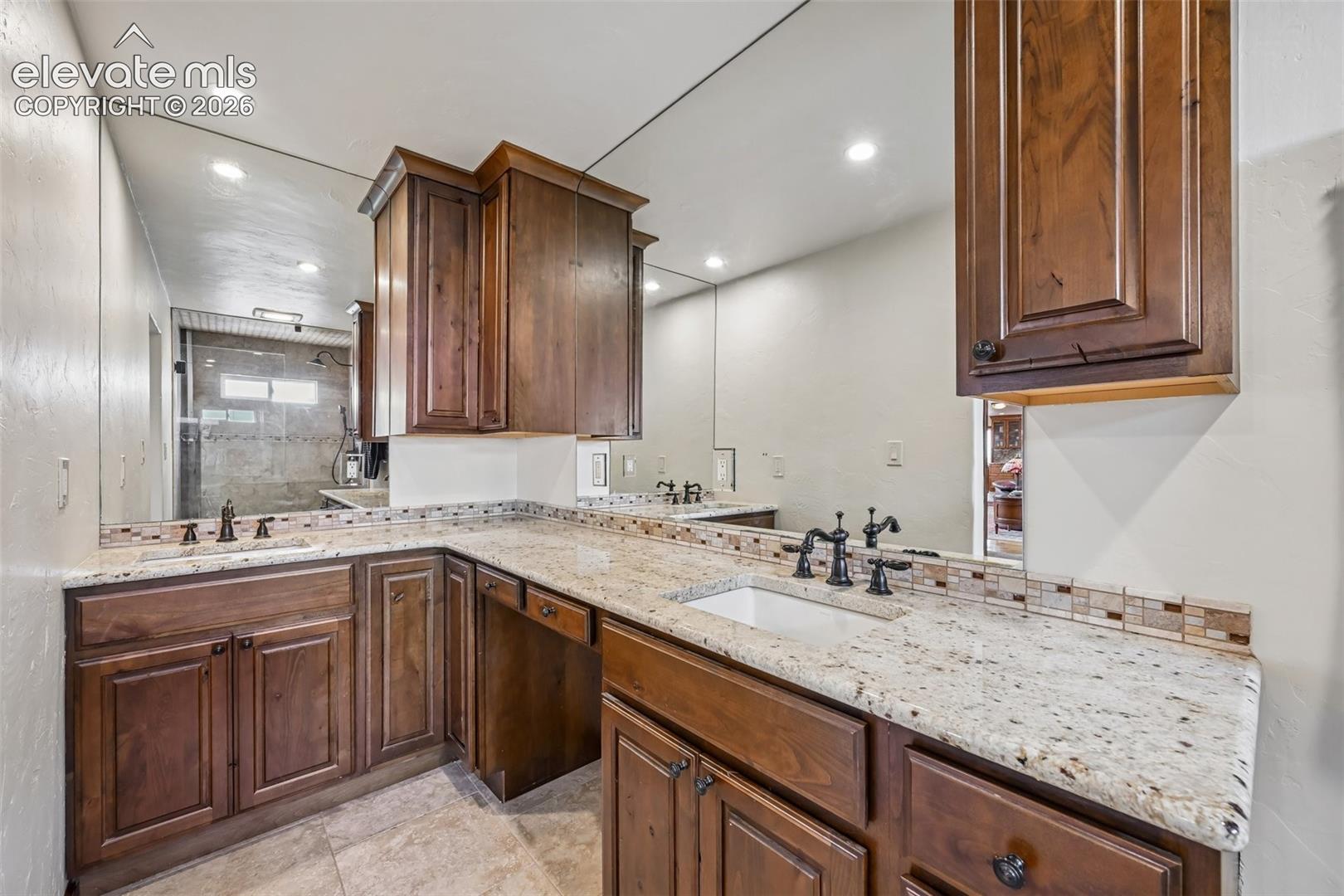 Bathroom vanity with a granite-style countertop, integrated sinks, and dark wood cabinetry