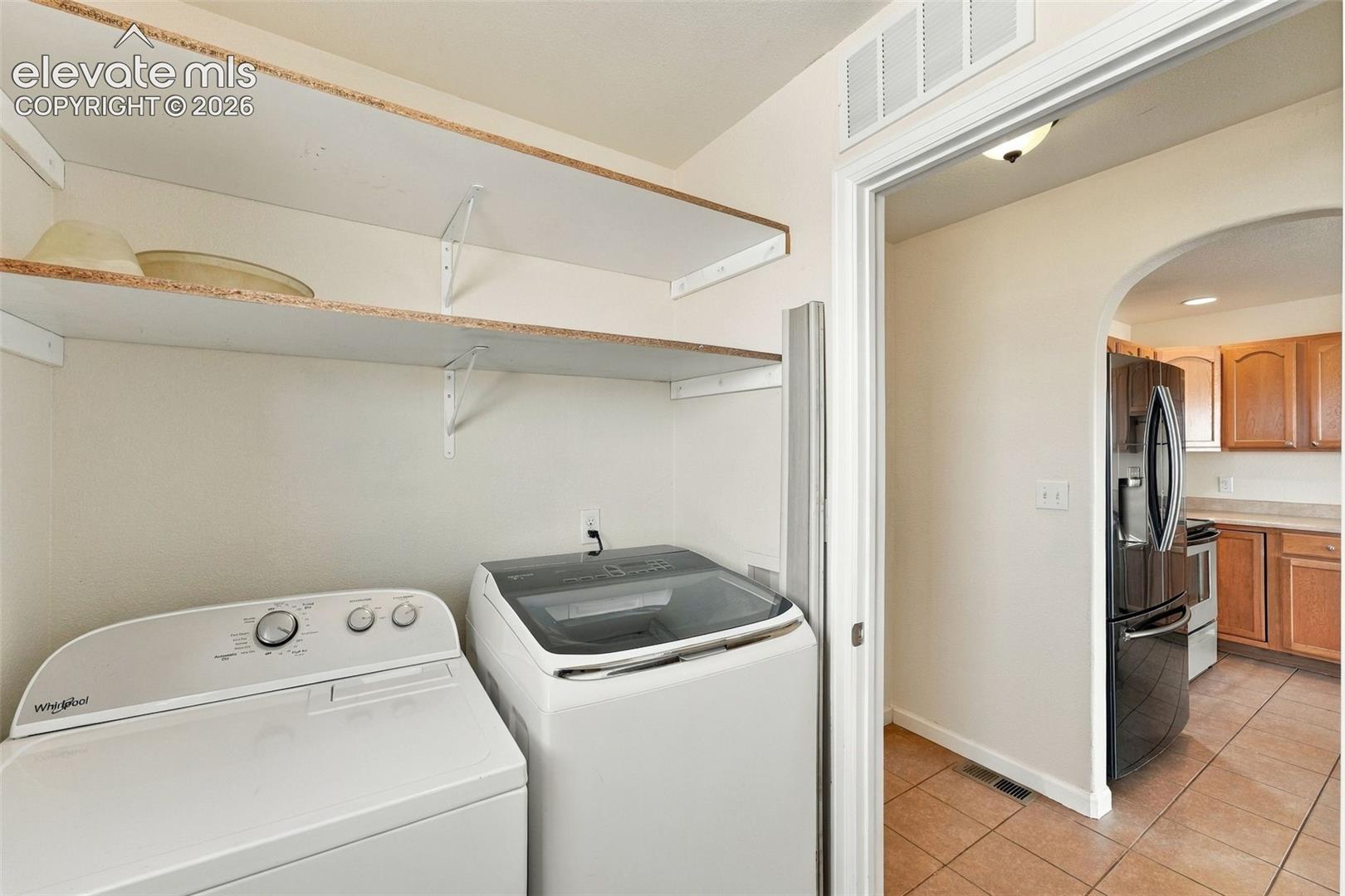 Laundry area featuring open wall-mounted shelving, neutral walls, and tile flooring