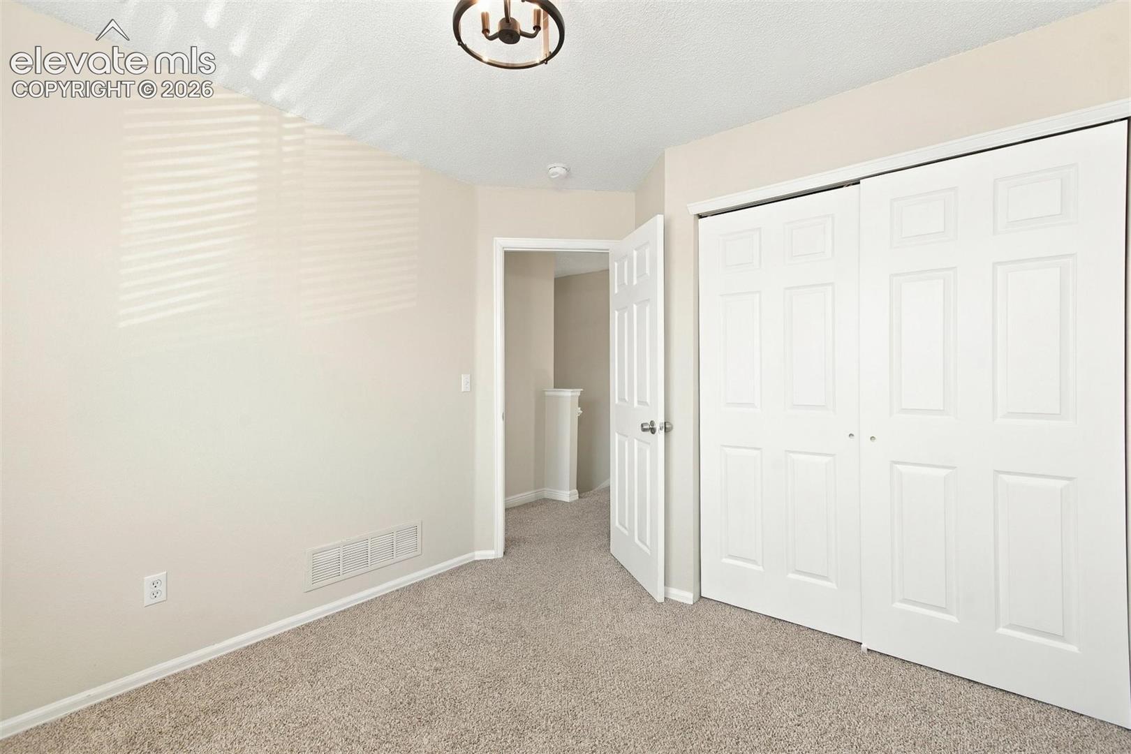 Neutral-toned interior featuring wall-to-wall carpeting, a dual-panel sliding closet, and a semi-flush mount light fixture