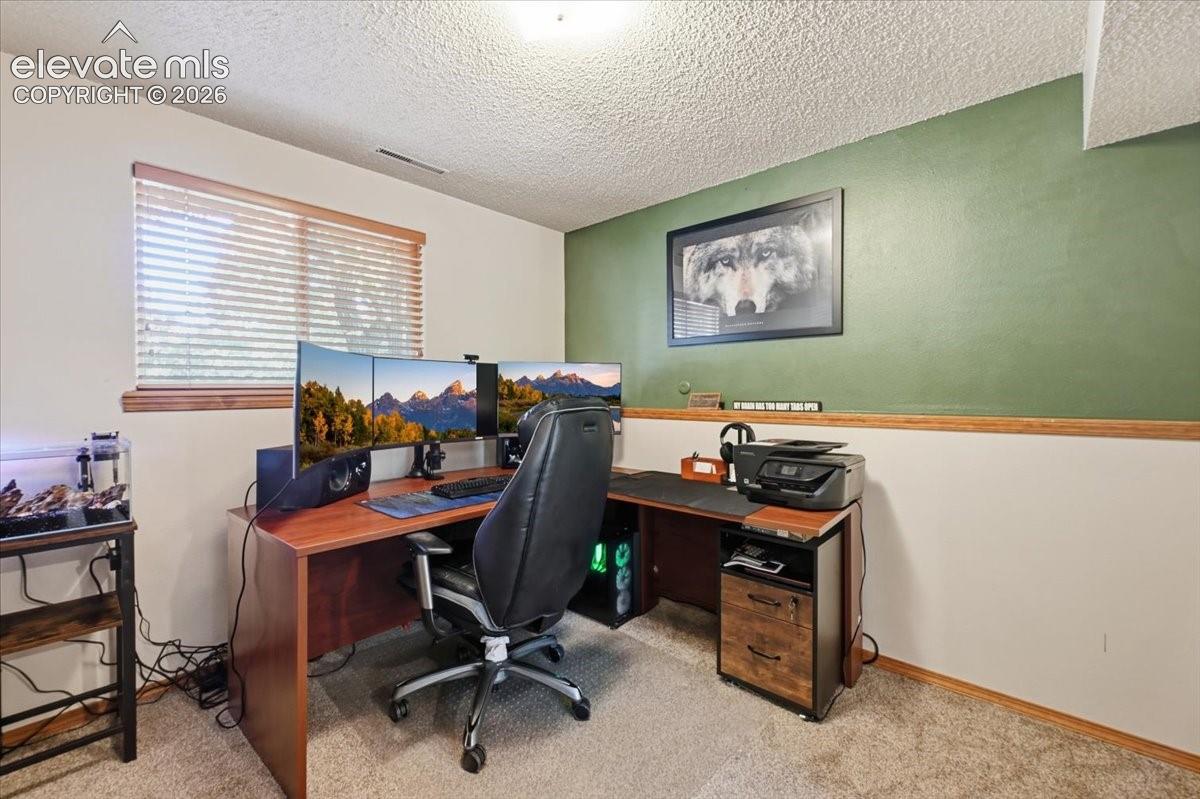 Wood-finish desk, wood trim, two-tone wall paint, and textured ceiling