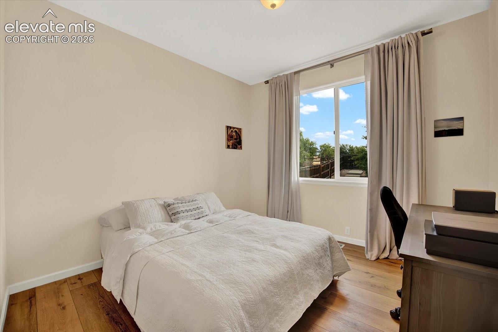Room featuring wood-finish flooring, neutral wall paint, and a single-pane window with a metal rod
