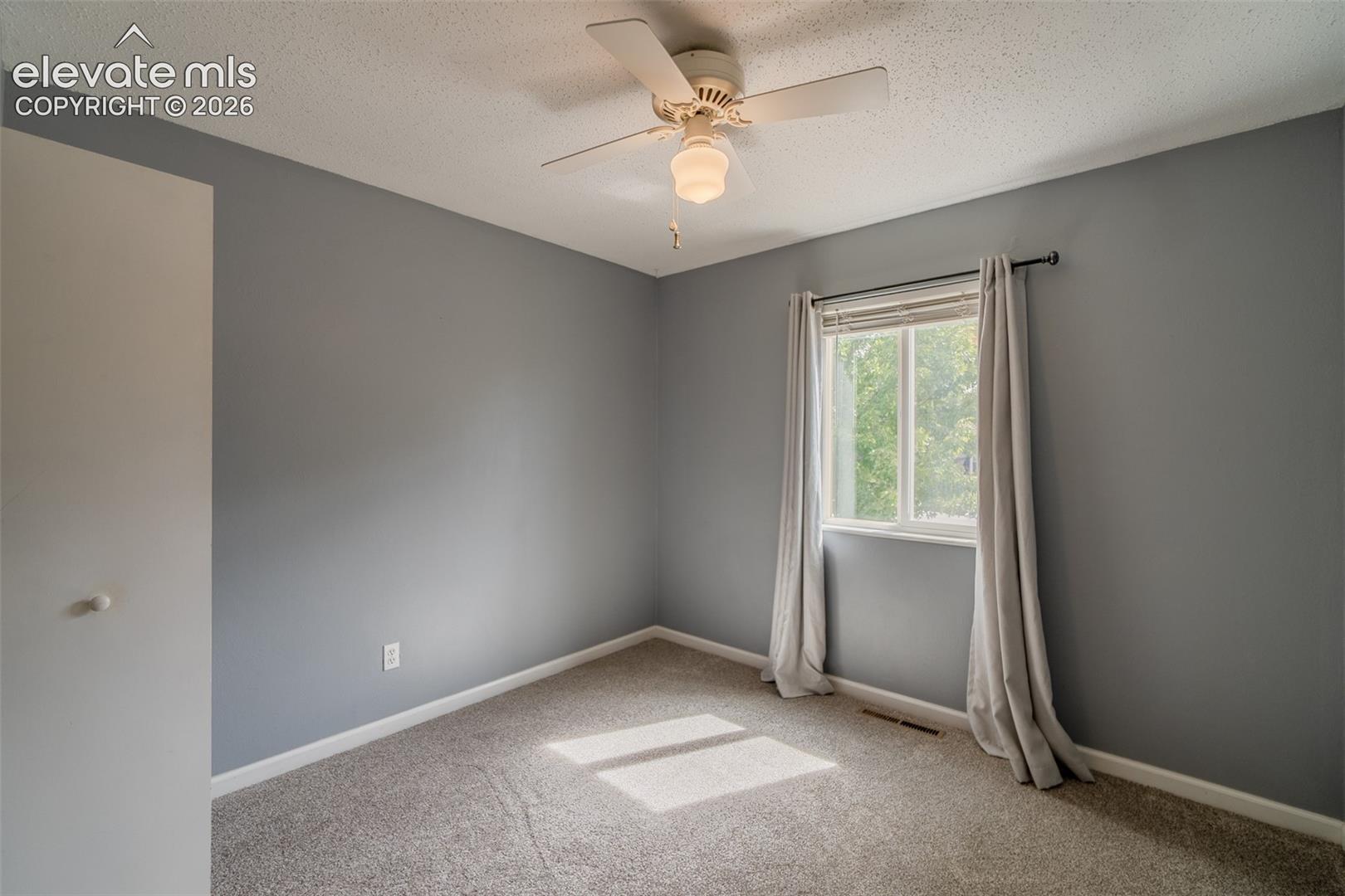 Wall-to-wall carpeting, a ceiling fan with integrated lighting, and a single window with blinds