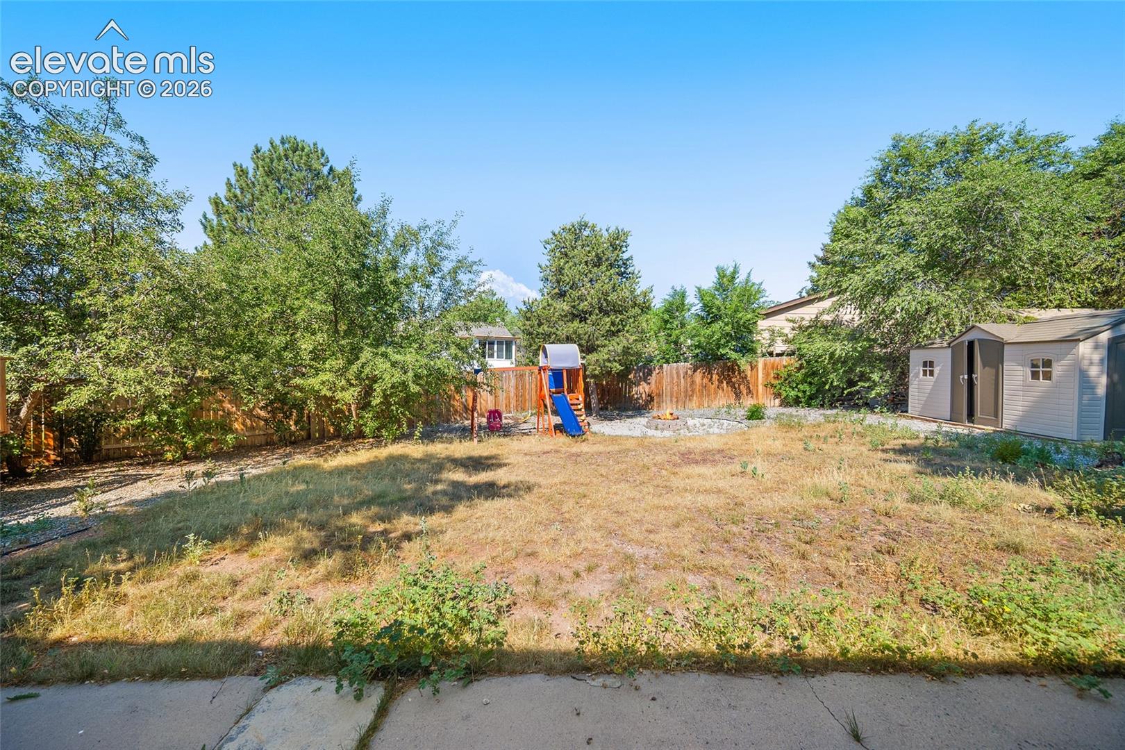 Fenced backyard with storage shed.