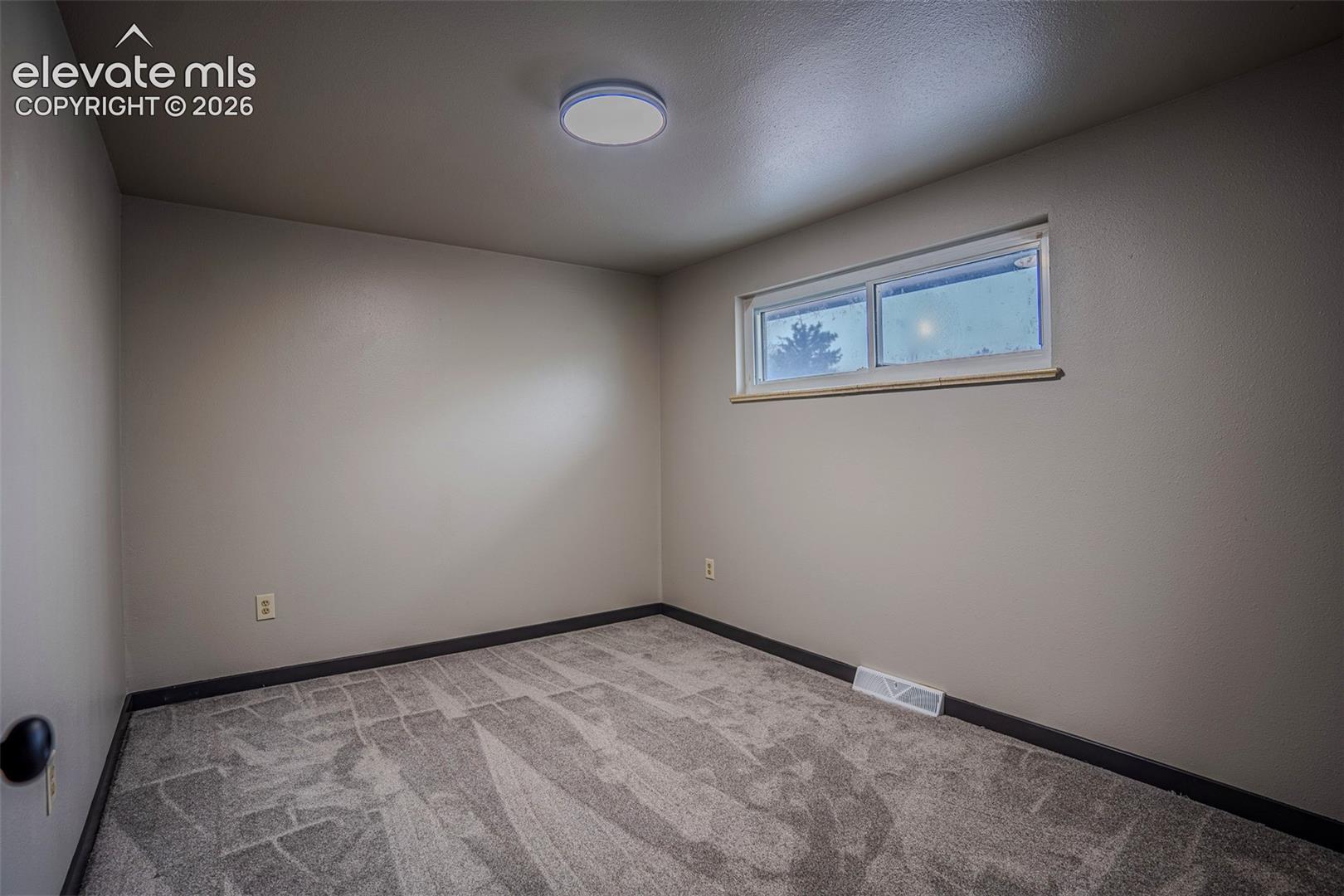 Neutral-toned walls, high-pile carpeting, horizontal sliding window, and flush-mount ceiling lighting