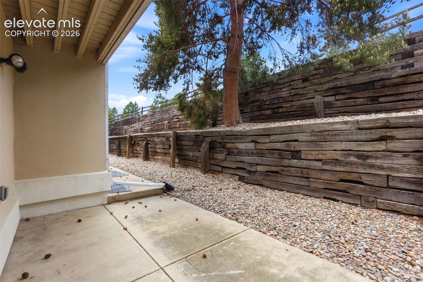 Concrete patio with stucco exterior and exposed wood beam soffit
