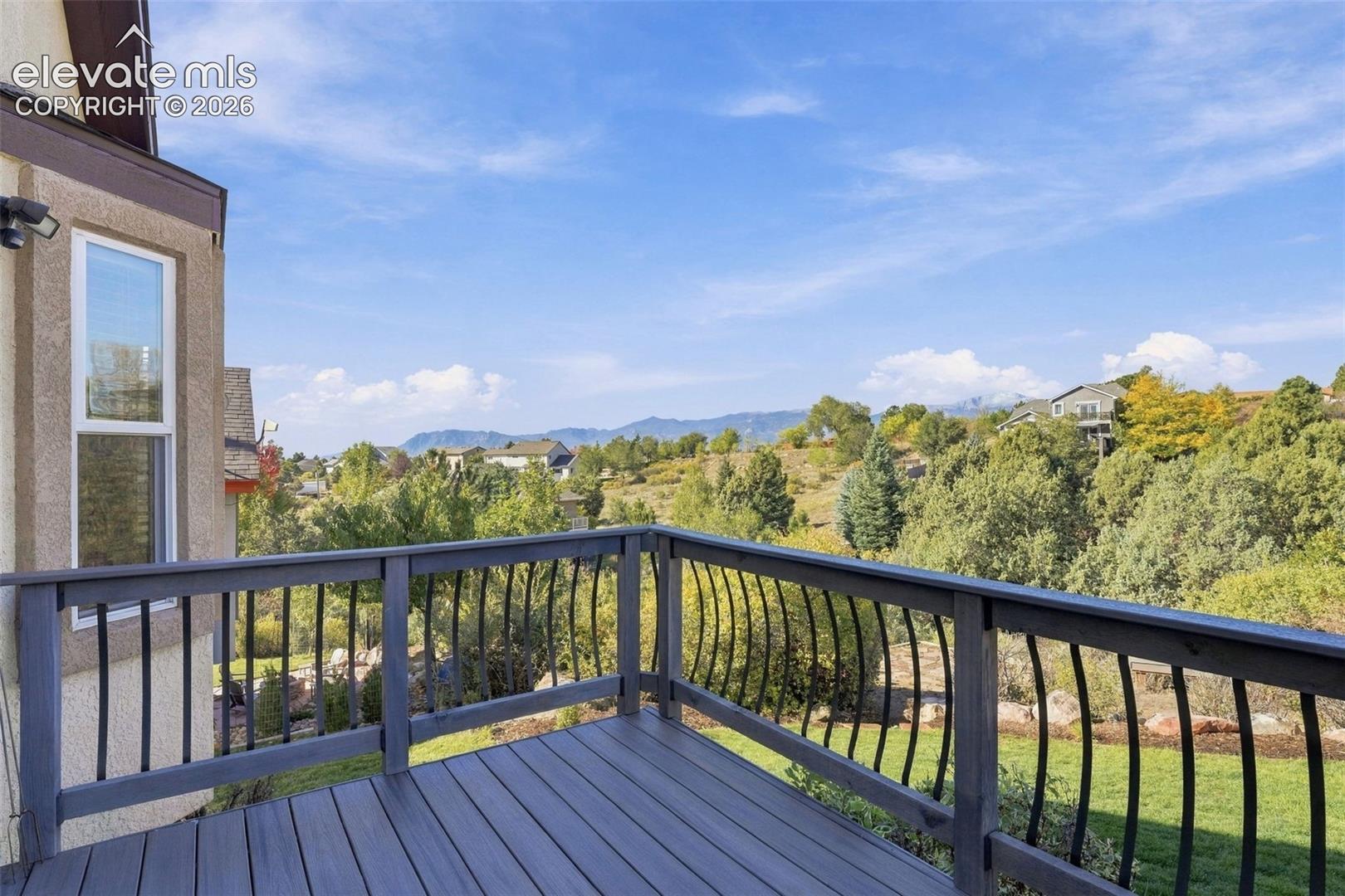 Exterior deck with composite flooring and decorative metal railing, showcasing mountain and treeline scenery
