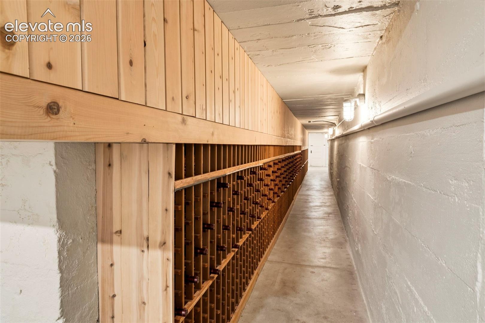 Custom built-in wood wine racking, wood-paneled accent wall, concrete flooring, and painted concrete masonry walls