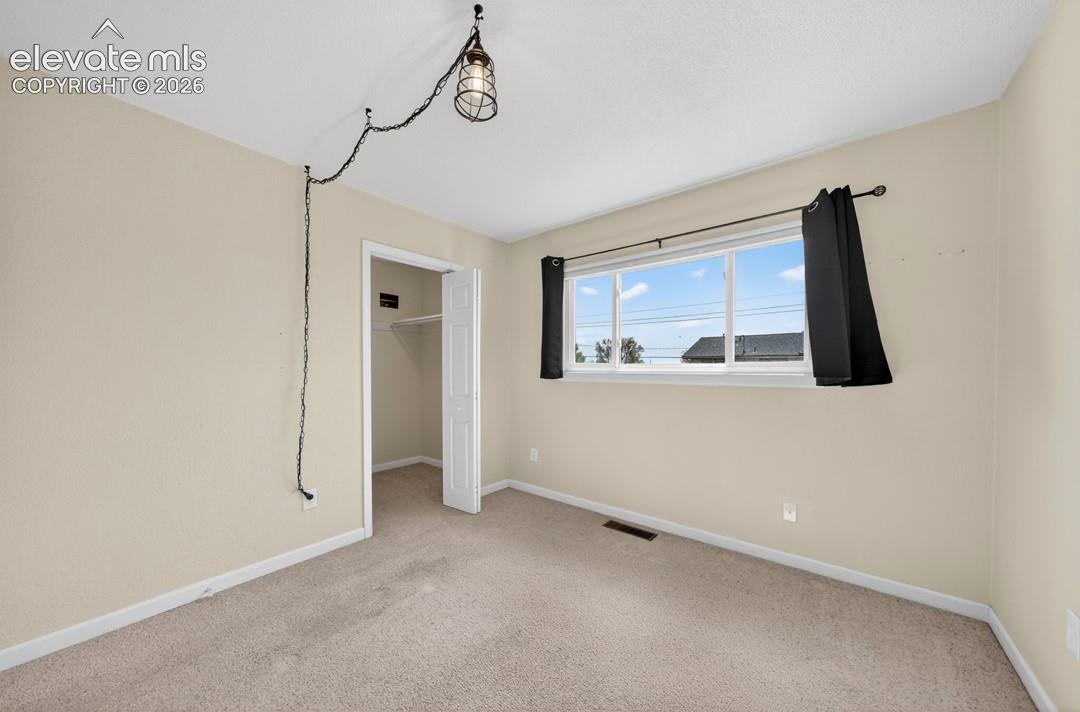 Neutral tone wall paint, light-toned carpeting, double-pane window, and white bi-fold closet door