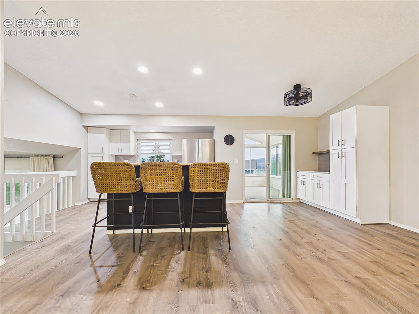 Renovated kitchen featuring a generous center island with seating, white cabinetry, stainless steel appliances, recessed lighting, and ample storage.