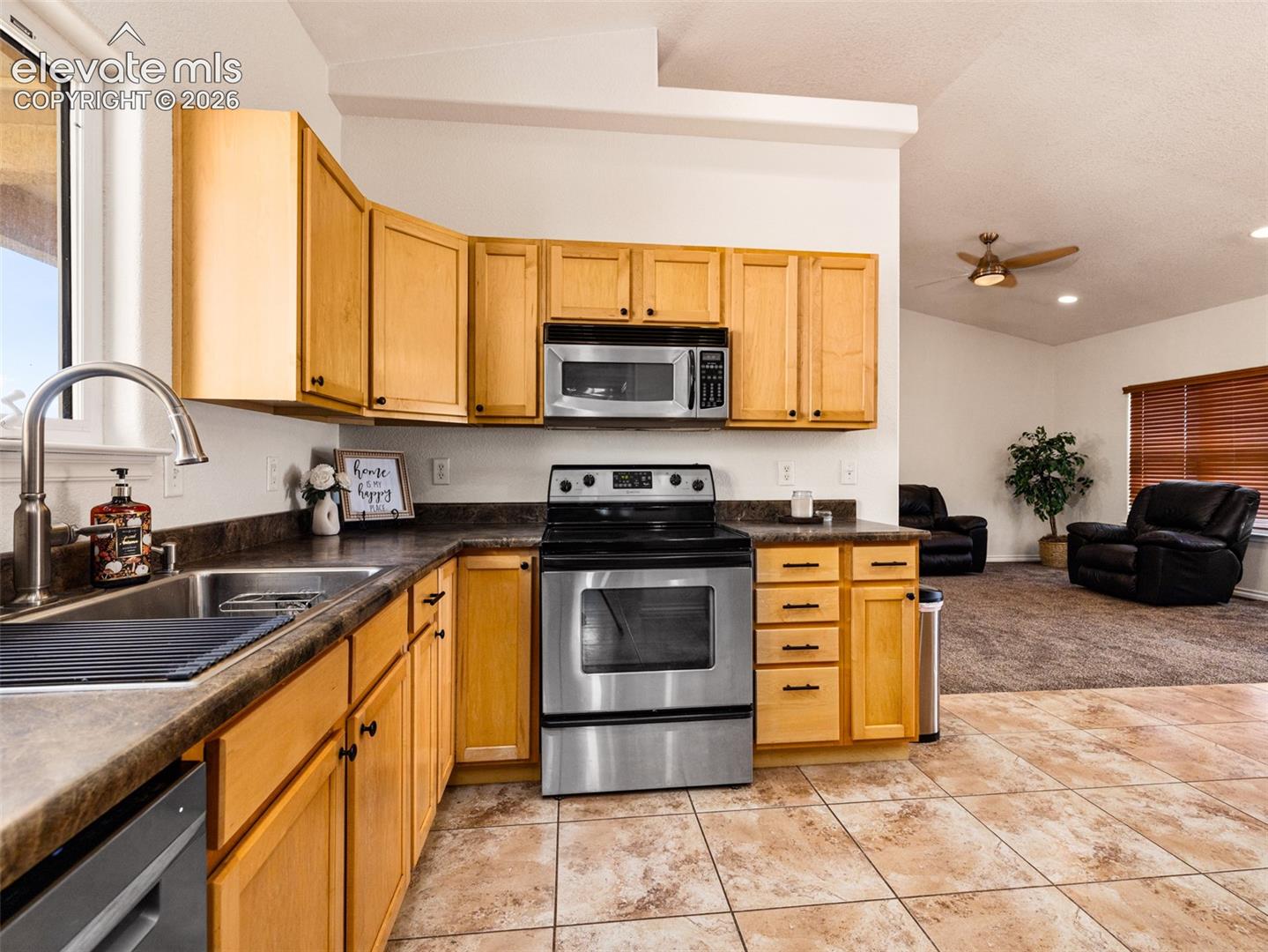 Kitchen featuring wood-finish cabinetry, stainless steel appliances, and a double basin sink with a high-arc faucet