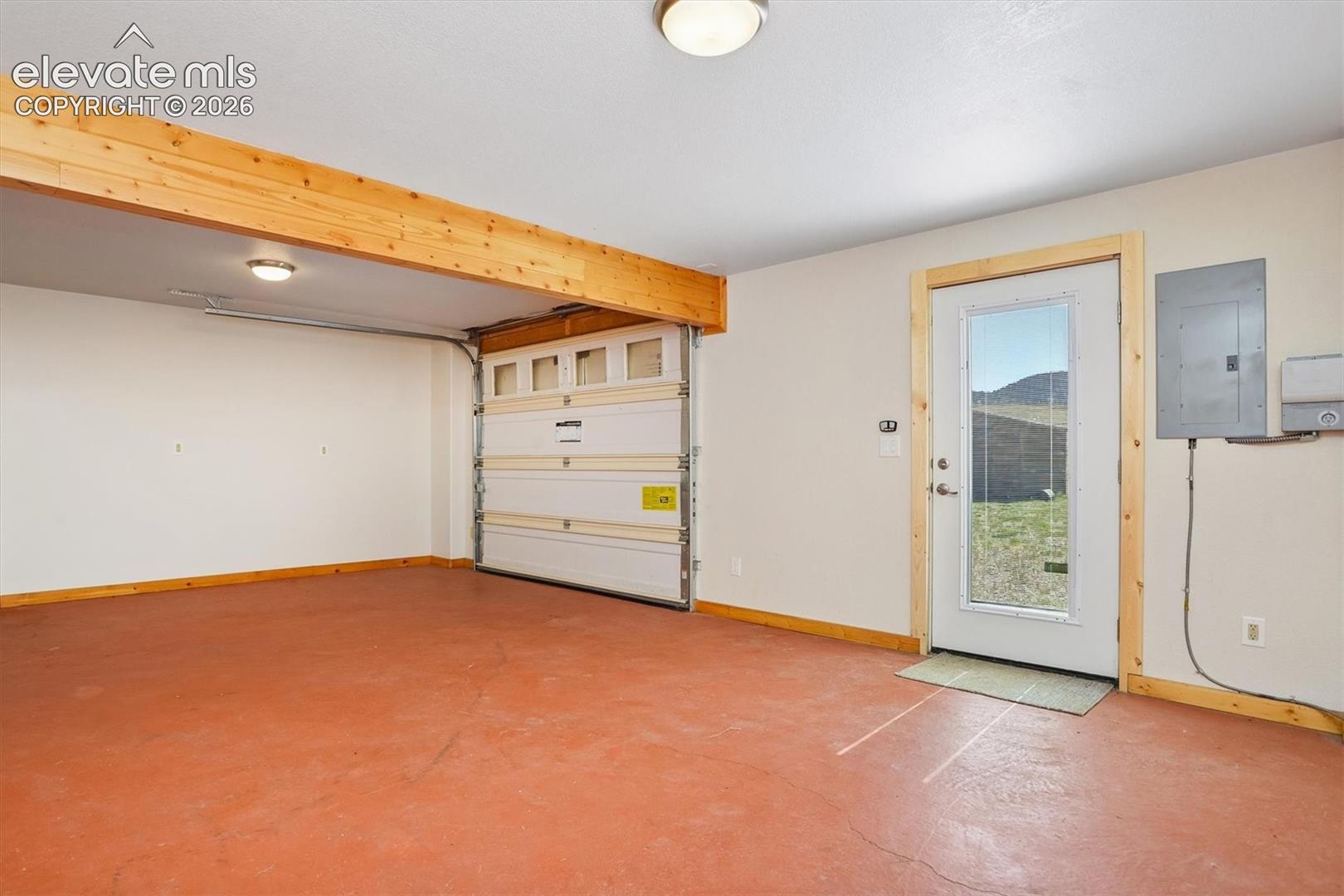 Spacious garage featuring a roll-up door, a painted concrete floor, and an exterior access door with a window