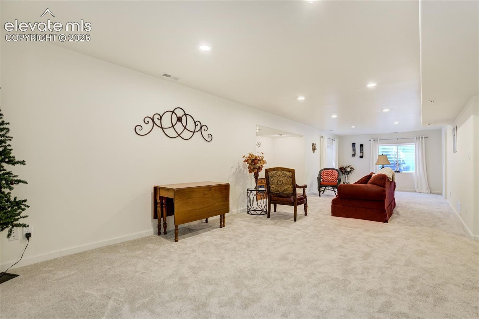 Neutral-toned carpeting, recessed ceiling lighting, and crisp white walls