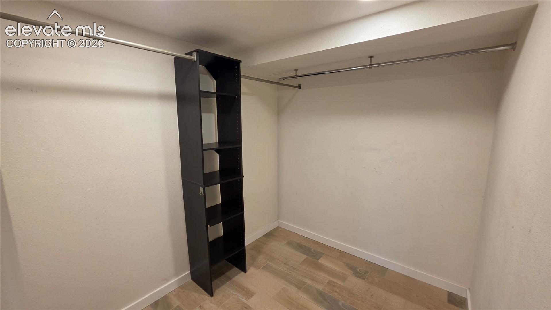 Built-in shelving unit, chrome hanging rods, recessed ceiling, wood-finish flooring