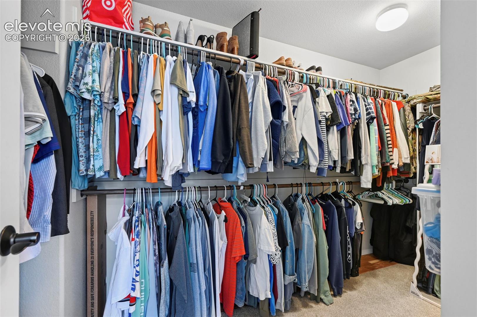 Walk-in closet featuring dual-tier metal rod shelving and carpeted flooring