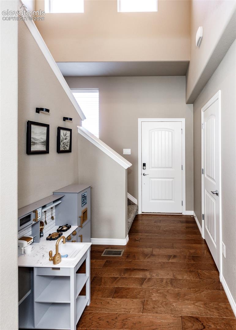 High-ceiling entryway featuring wood-finish flooring, multi-level windows, and paneled interior doors