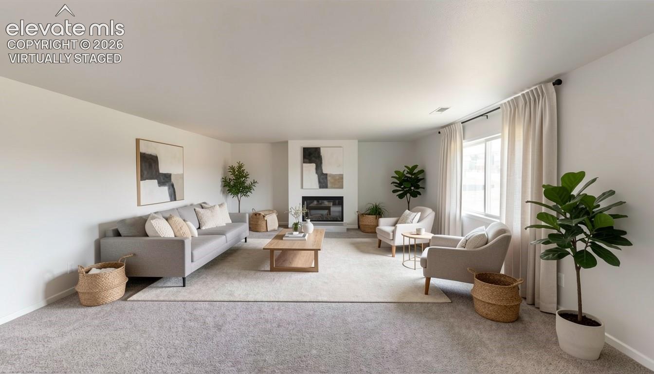 virtually staged.Carpeted living area featuring a fireplace with a white mantel, light-toned walls, and a window with drapery