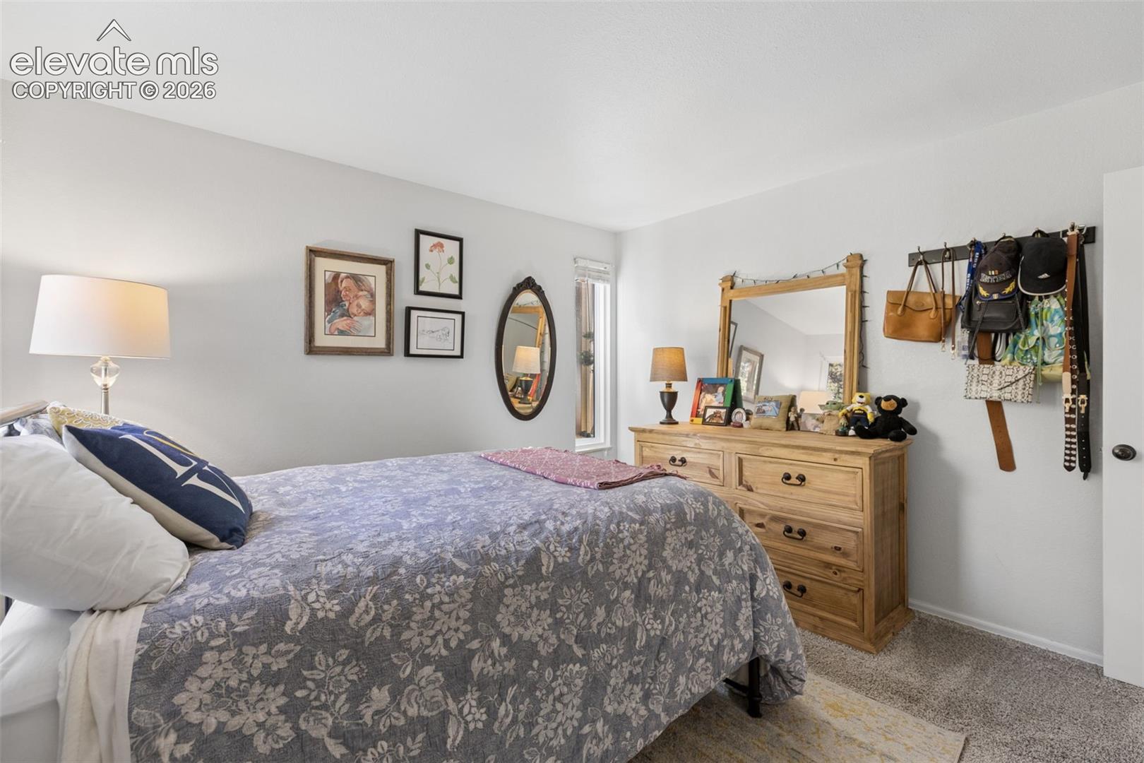 Light gray wall paint, recessed window, light wood-finish dresser with mirror, and gray carpet
