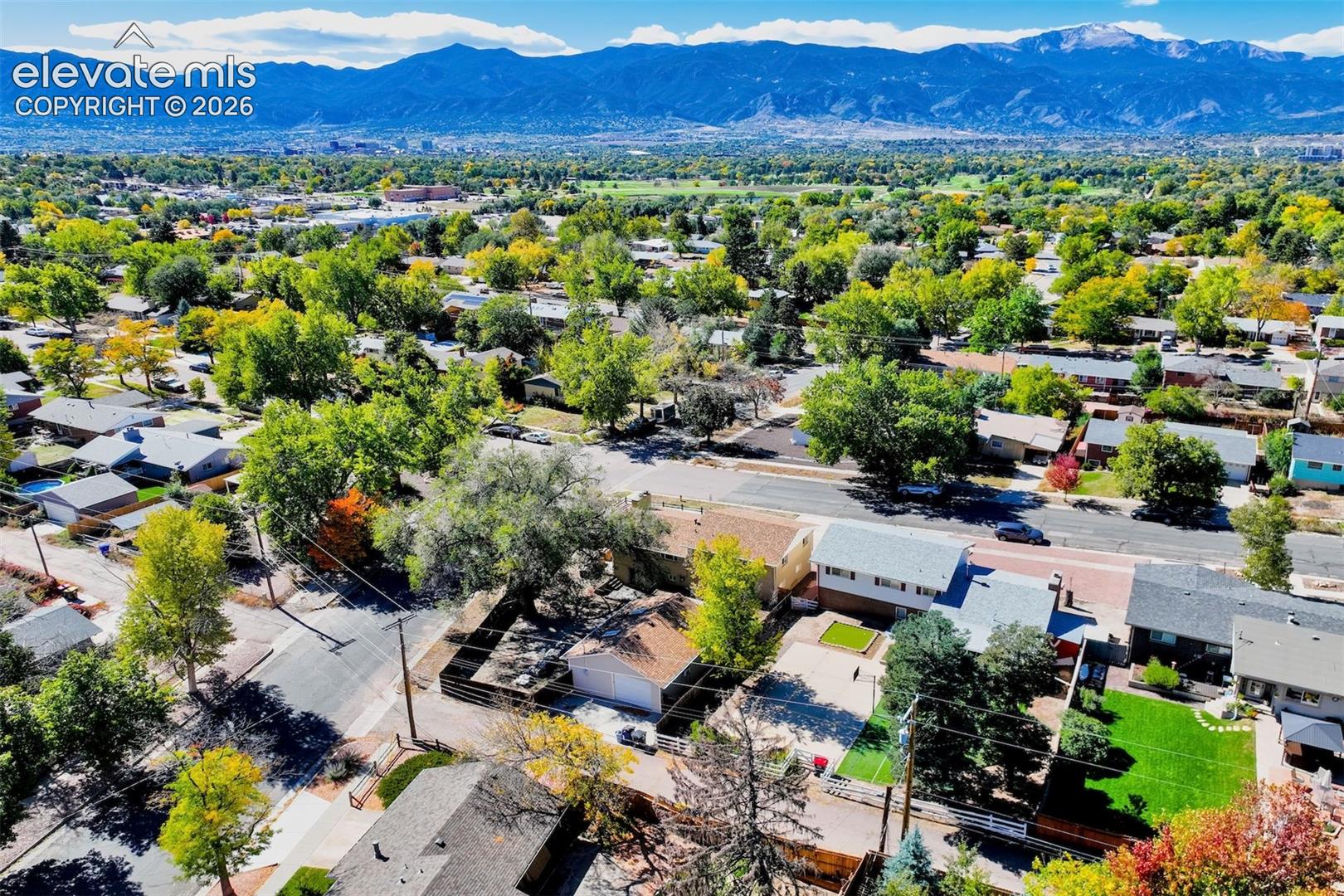 Aerial perspective featuring mountain range backdrop, mature canopy trees, and established neighborhood landscaping