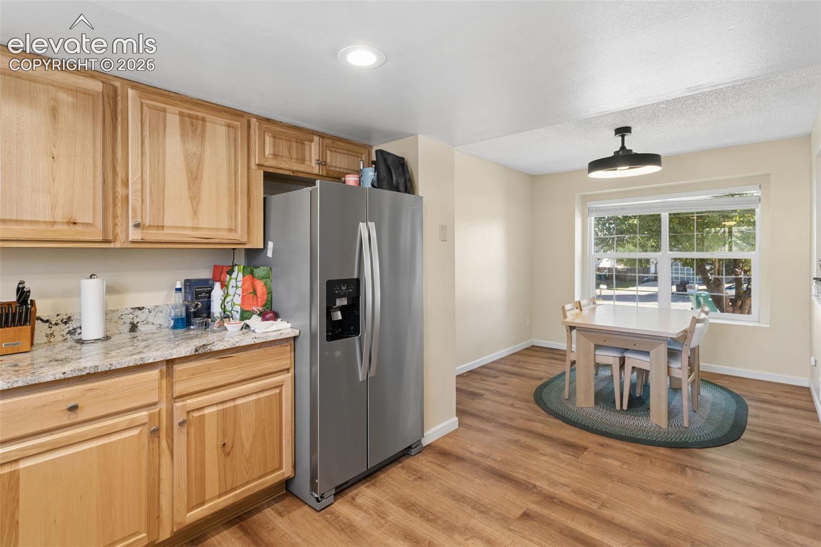Kitchen with natural wood cabinetry, light-toned countertops, and wood-finish flooring