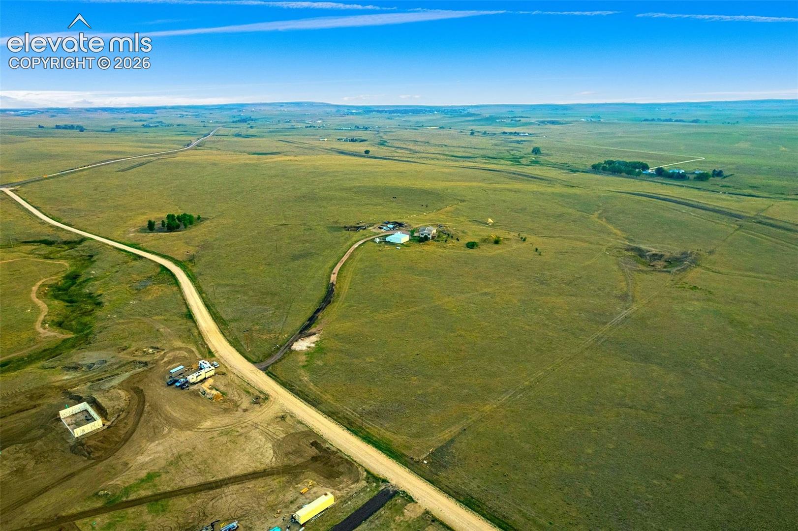 Expansive acreage featuring rolling terrain, vast open grasslands, gravel road access, and distant horizon scenery