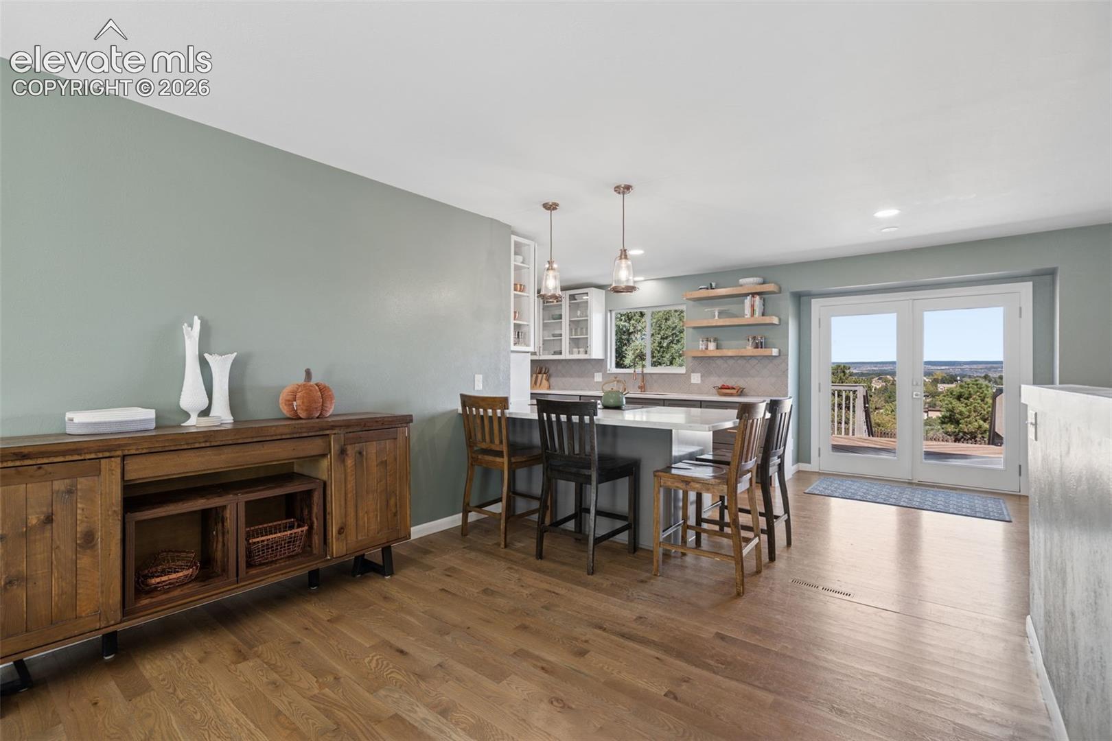 Kitchen featuring a central island with quartz countertops, wood-finish flooring, floating shelves, recessed lighting, and double glass-paned doors