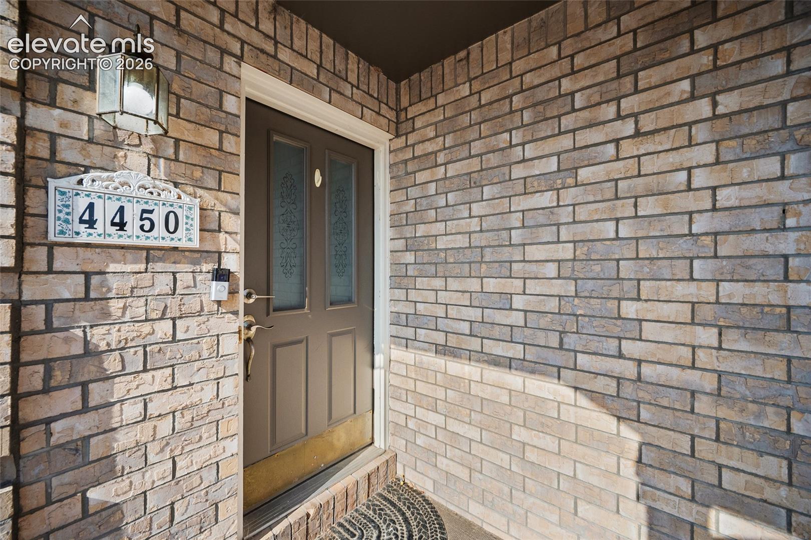 Brick exterior with decorative house numbers and an exterior wall lantern