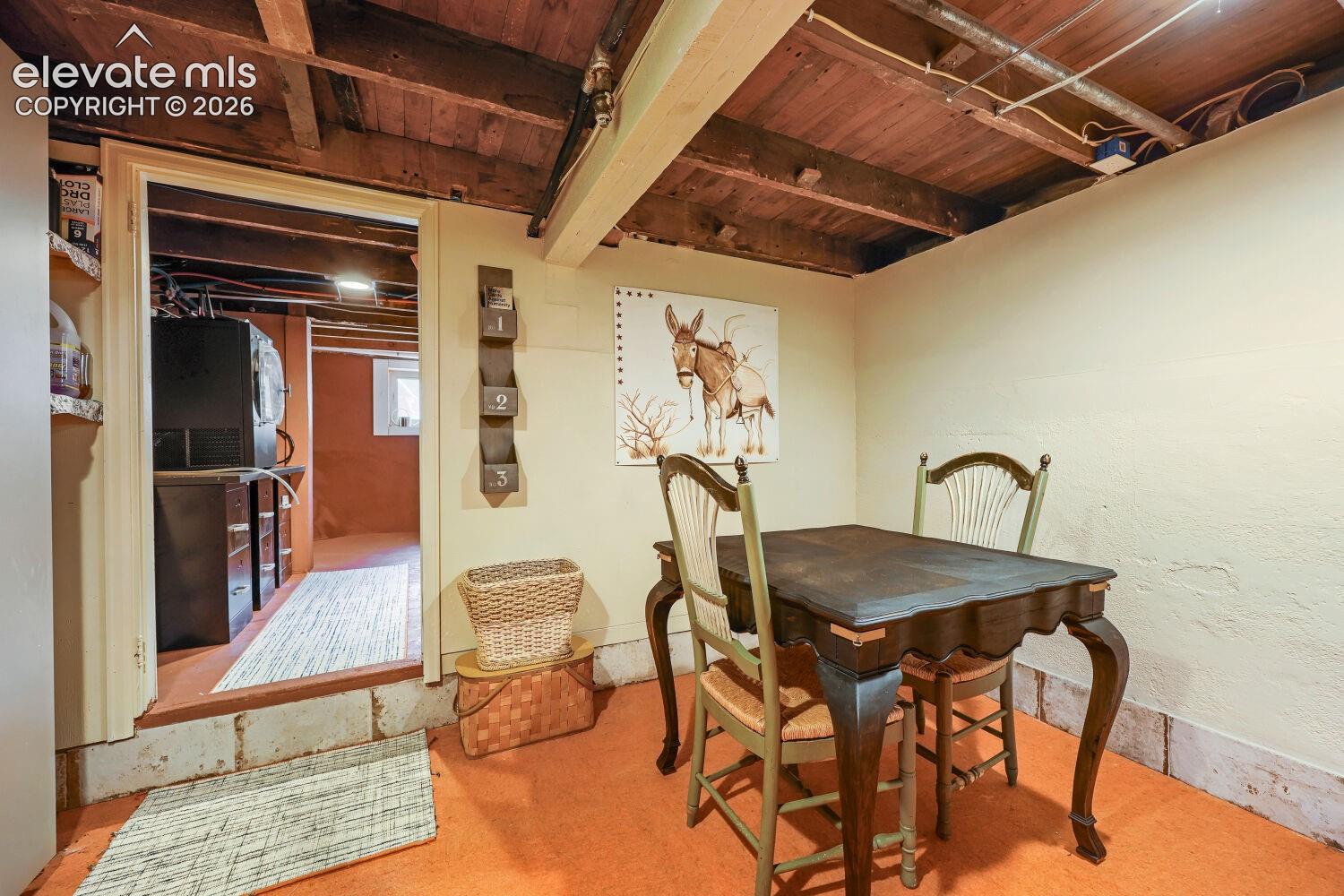 Exposed wood beam ceiling, textured wall finish, and wood-finish flooring